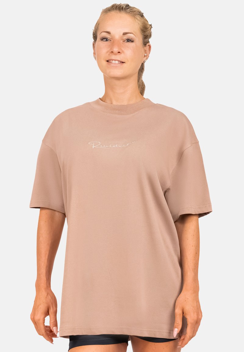 Overmaat t-shirt in lichtbruin katoen, met korte mouwen, een ronde hals en kleine witte tekstdetails op de borst.