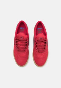 Punaiset mokkaisesti tenniskenkä, joissa on tekstuuri pintakäsittely, nauhat, kumipohja, ja tummanharmaat yksityiskohdat sivuilla.