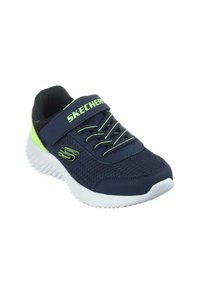 Sneaker in rete navy con dettagli verde neon, suola in gomma bianca, lacci elastici e strap regolabile con il logo "SKECHERS" sul lato.