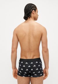 Μαύρο μποξεράκι από ελαστικό υλικό, με επαναλαμβανόμενο λευκό τριγωνικό σχέδιο. Ελαστική ζώνη στη μέση για άνεση και εφαρμογή.