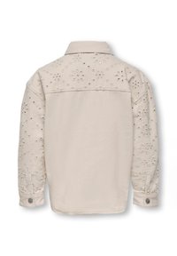 Kreminės spalvos švarkas su siuvinėtų gėlių raštais ir karoliukų akcentais ant pečių ir rankovių. Yra apykaklė ir mygtukiniai rankogaliai.