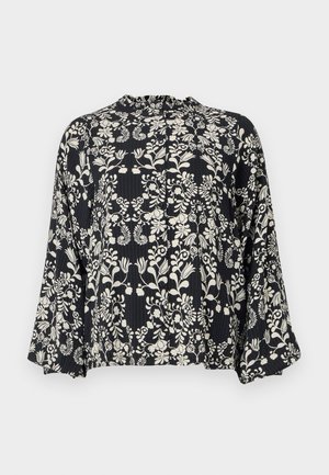 Blusa negra con un estampado floral en blanco, con un escote con volantes y mangas sueltas y acampanadas. Tela texturizada con líneas verticales.