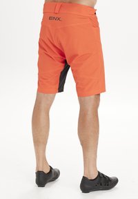 Orange shorts med svarta accenter, texturerad tyg, mitt-lår längd, med logotypen "ENX" på baksidan och sidofickor för förvaring.
