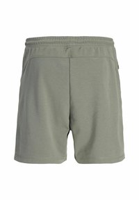 Shorts de sport verts avec une ceinture élastique, fabriqués en tissu doux, présentant un design simple et des poches latérales.