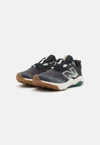 Zapatillas deportivas negras y grises con parte superior de malla, suela de goma y acentos verdes; cuentan con una puntera texturizada y un cuello acolchado.