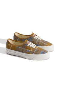 Brown and blue plaid canvas sneakers with white rubber soles and laces. Vans logo on side, rounded toe, and low-top design.