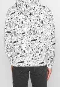 Felpa con cappuccio bianca con motivo di personaggi dei cartoni animati neri, che includono attrezzature sportive e disegni giocosi. Tessuto morbido con vestibilità comoda.