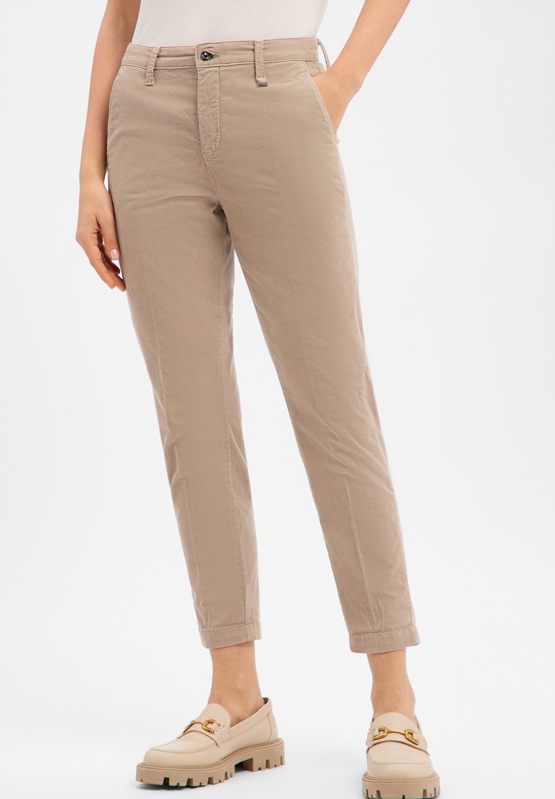 Beige cotton trousers with a slim-fit design, featuring front pockets, a zip fly, and rolled cuffs. Paired with light-colored loafers.