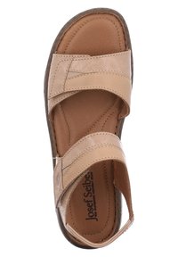 Beige nahkasaapas, jossa on kaksi leveää säädettävää remmiä, pehmustettu pohjallinen ja tumman kontrastinen pohja. Tasainen pinta, jossa on minimaalinen ommel.