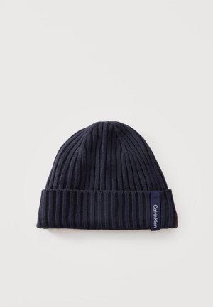 Dunkel marineblaue gerippte Strickmütze mit umgeschlagenem Bündchen und sichtbarem Calvin Klein Markenlabel am Bündchenrand.