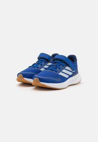 Baskets de sport bleues avec une tige en maille, accents blancs et une sangle Velcro. Comprend une semelle en caoutchouc et un col rembourré pour le confort.