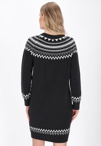 Abito nero lavorato a maglia con un motivo geometrico bianco attorno al collo e ai polsini, maniche lunghe e vestibilità comoda.
