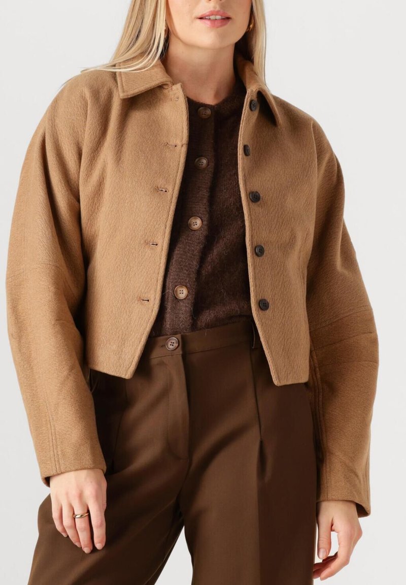 Bruine cropped jas van gestructureerde stof, met een kraag, knopen aan de voorkant en brede mouwen, gecombineerd met een bijpassende top en broek.