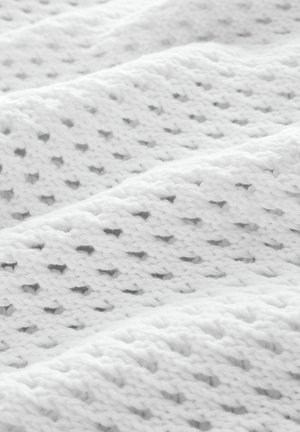 Tissu tricoté blanc présentant un motif texturé avec de petits trous, mettant en valeur une apparence douce, légère et aérée.