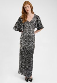 Abito da sera nero con paillettes e decorazioni argentate, scollatura a V, maniche svasate e motivi intricati. Silhouette aderente con orlo dritto.