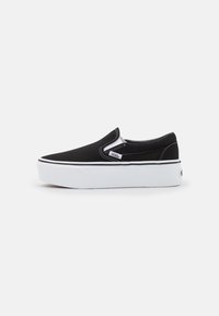 Black canvas slip-on shoe with white rubber sole, featuring elastic side accents and contrasting stitching. Classic low-profile design.