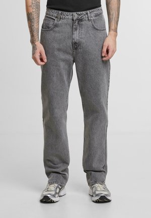 Grå denimjeans med en avslappet passform, med beltehemper, fem lommer og subtil tekstur. Brukt med grå og sølvfargede joggesko.