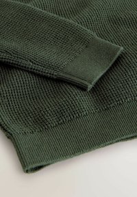 Maglione lavorato a maglia verde scuro con un motivo testurizzato, con polsini e orlo a coste, che mette in mostra dettagli di cucitura variati.