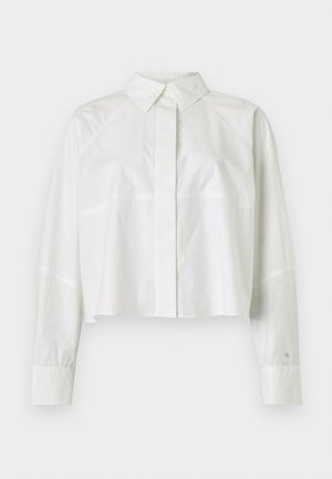 White cropped shirt made of cotton. Features a classic collar, long sleeves with buttoned cuffs, and subtle seam detailing.
