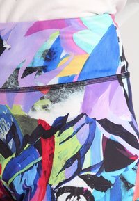 Leggings elasticizzati con un motivo astratto colorato in tonalità di viola, blu, verde e rosso, con una texture liscia e opaca e una vita elastica.