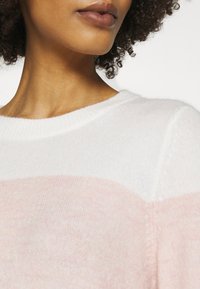 Lightweight, knitted sweater featuring a round neckline, white body, and soft pink horizontal stripes, highlighting a delicate texture.