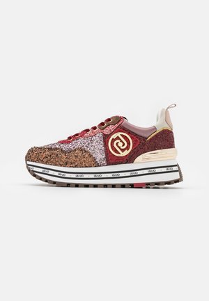 Sneaker met lage zool en glinsterende roze, rode en bruine panelen, gouden logo-accent, gevoerde kraag en wit merkzool met diepe groeven.