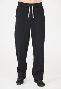 Zwarte joggingsbroek met een zachte textuur, elastische tailleband, grijze trekkoord en zijzakken. Draag met zwarte sportschoenen.