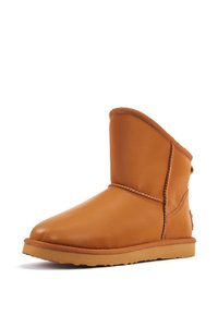 Helle Leder-Ankle-Boots mit runder Spitze, weicher Textur und sichtbaren Nähten; verfügen über eine flexible Gummisohle und einen umklappbaren Kragen.