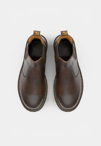 Braune Leder-Ankelstiefel mit elastischen Seiteneinsätzen, gelben Nähten und Ziehschlaufen. Glatte Textur mit einem runden Zehendesign.