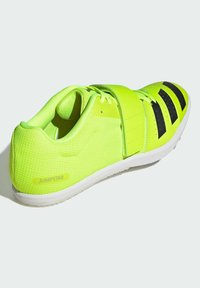Scarpa sportiva di un brillante giallo neon con texture in rete, strisce nere di accentuazione e un cinturino in Velcro. Suola in gomma bianca con dettagli di battistrada.