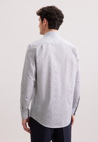 Camicia azzurra a righe con maniche lunghe, orlo arrotondato e un sottile motivo floreale. Presenta polsini abbottonati e colletto classico.