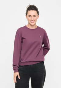 Felpa girocollo viola con polsini e fondo a costine, caratterizzata da un piccolo logo bianco a forma di albero sul petto. Tessuto morbido e texture.