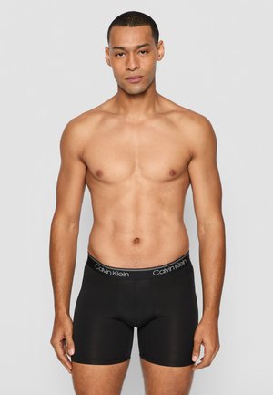 Schwarze Boxer-Briefs mit glatter Textur, versehen mit einem weißen, mit Logo bedruckten elastischen Bund. Das Design ist eng anliegend und betont eine schlanke Silhouette.