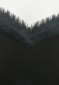 Czarno-biała odzież z postrzępionym, postrzępionym dołem o teksturowanej czarnej krawędzi, kontrastującą z gładkim białym materiałem powyżej.