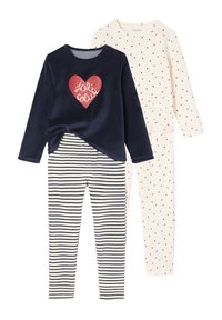 Two sets of children's pajamas: a navy top with a red heart design and striped bottoms, and an off-white top with red heart patterns and matching pants.