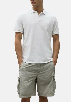 Camisa polo de algodón blanca con cuello y tapeta de dos botones, combinada con pantalones cortos cargo gris claro que presentan bolsillos laterales y un corte relajado.