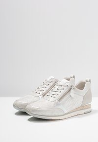 Jasnoszare buty sportowe z teksturowaną cholewką, sznurowaniem, bocznym zamkiem oraz subtelnym klinem z korka.