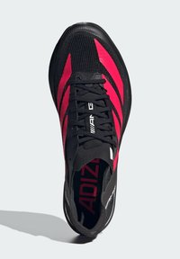 Czarne buty sportowe z teksturowaną cholewką, ozdobione wyrazistymi różowymi paskami. Posiadają płaską podeszwę i sznurowaną konstrukcję. Wnętrze z logo marki.