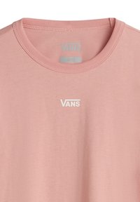 T-shirt en coton rose avec un col rond ; présente un logo 'VANS' blanc sur la poitrine ; l'étiquette indique la taille 'Petite'. Texture lisse.