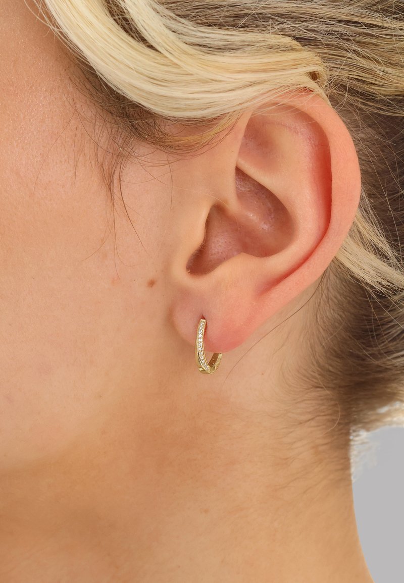 Goldener Creolen-Ohrring mit geschwungenem Design, auf einer Seite mit einer Reihe kleiner Diamanten besetzt, glatte Oberfläche und glänzendes Finish.