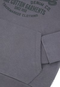 Sweat-shirt gris en coton, doté d'une poche kangourou et de poignets côtelés. Il présente un logo imprimé en vert foncé sur le devant.