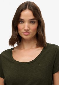 Olivengrønt kortærmet t-shirt med rund hals, lavet af blødt stof, med et lille logo broderet nær halsudskæringen.