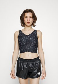 Top atlético cropped preto com tecido texturizado e padrão floral, combinado com calções pretos brilhantes com cintura elástica e logótipo.