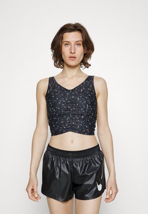 Top atlético cropped preto com tecido texturizado e padrão floral, combinado com calções pretos brilhantes com cintura elástica e logótipo.