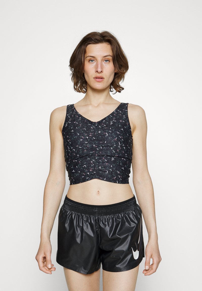 Top atlético cropped preto com tecido texturizado e padrão floral, combinado com calções pretos brilhantes com cintura elástica e logótipo.