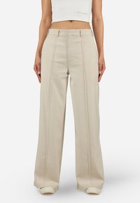 Beige wide-leg trousers made of smooth fabric, featuring front pleats, a tailored design, and a small logo detail on the front.
