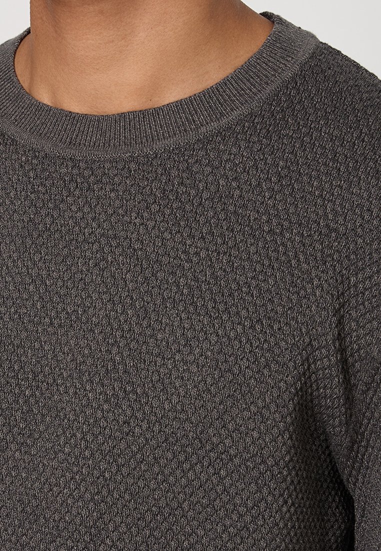 Suéter gris de punto con un patrón texturizado, escote redondo y puños acanalados. El tejido parece suave y duradero.