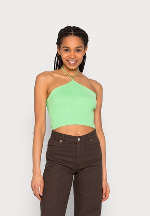 Top cropped halter verde com um design ajustado, apresentando uma alça atada e um decote reto. Combinado com jeans de cintura alta castanho escuro.