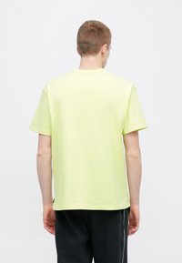 Ανοιχτό κίτρινο κοντομάνικο T-shirt με στρογγυλή λαιμόκοψη, κατασκευασμένο από μαλακό βαμβακερό ύφασμα, διαθέτει χαλαρή γραμμή και ίσια ραφή στο τελείωμα.