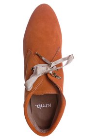 Chaussure en suédine orange rouille à lacets beige, œillets en métal et bout arrondi, vue de dessus.